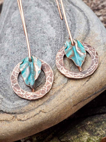 Beautiful handmade copper earrings displayed on the grey rock